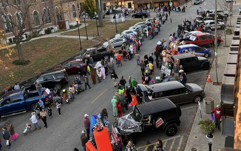 birds eye view of street filled with trucks and cars giving out candy to youngsters